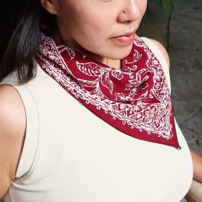Person wearing a red bandana with white patterns on a neutral background