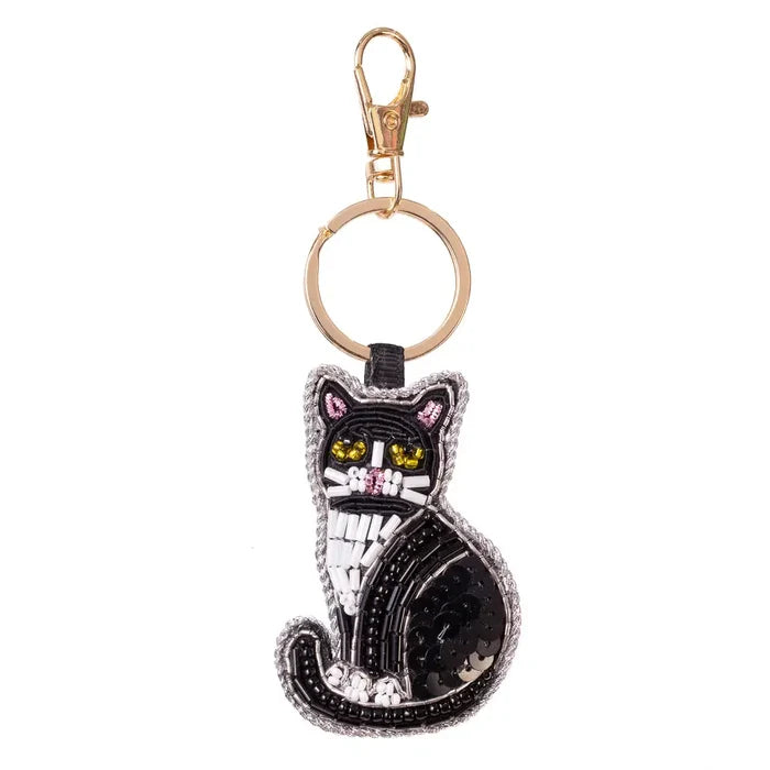A black cat-shaped keychain charm with embroidered details, yellow eyes, and a gold-tone clasp on a plain white background.