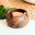 Wooden cat-shaped bowl with salt on a textured surface