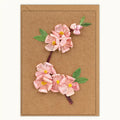 A rectangular kraft paper card featuring a raised, dimensional floral design of pink blossoms with green leaves and yellow centers on a brown kraft background.