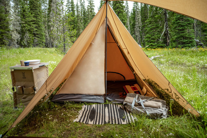 Chimaki Tent tan tipi with dark gray floor in grassy forest clearing