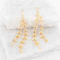 Gold dangle earrings on a marble surface