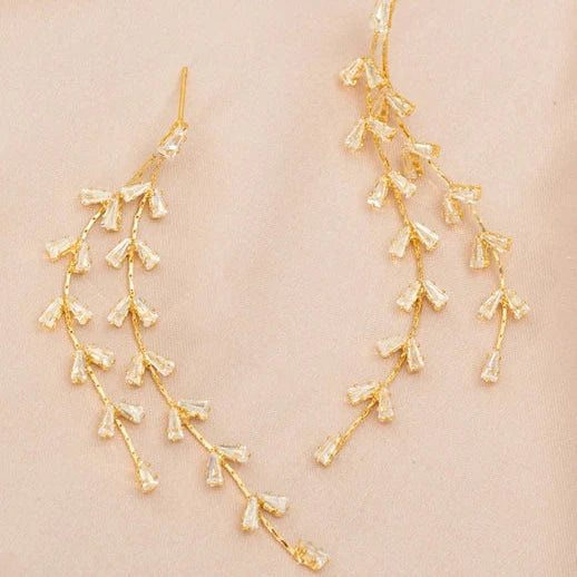 Gold floral earrings on a beige background
