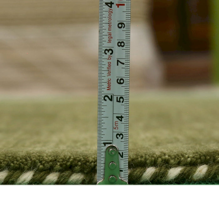 Wool area rug with green pile and white stripe detail, measured depth with tape