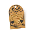 Heart-shaped gold bookmark on a brown card with 'all you need is love' text, on a white background.