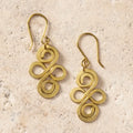 Pair of gold spiral earrings on a beige stone surface