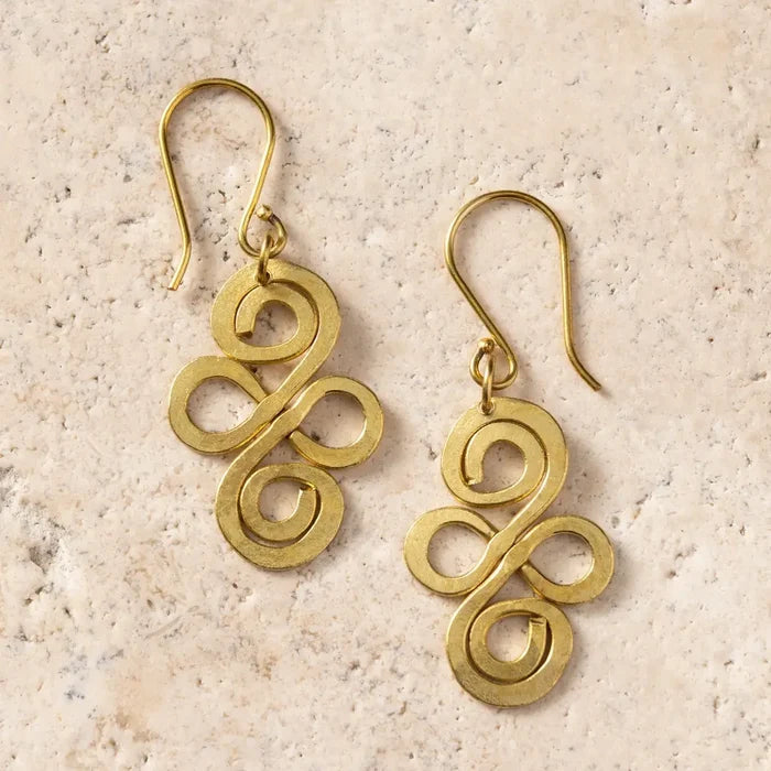 Pair of gold spiral earrings on a beige stone surface