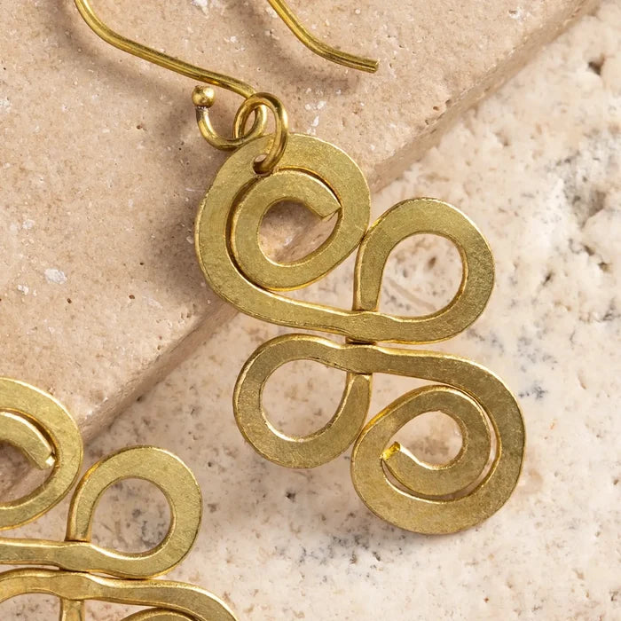Gold spiral earrings on a textured beige surface