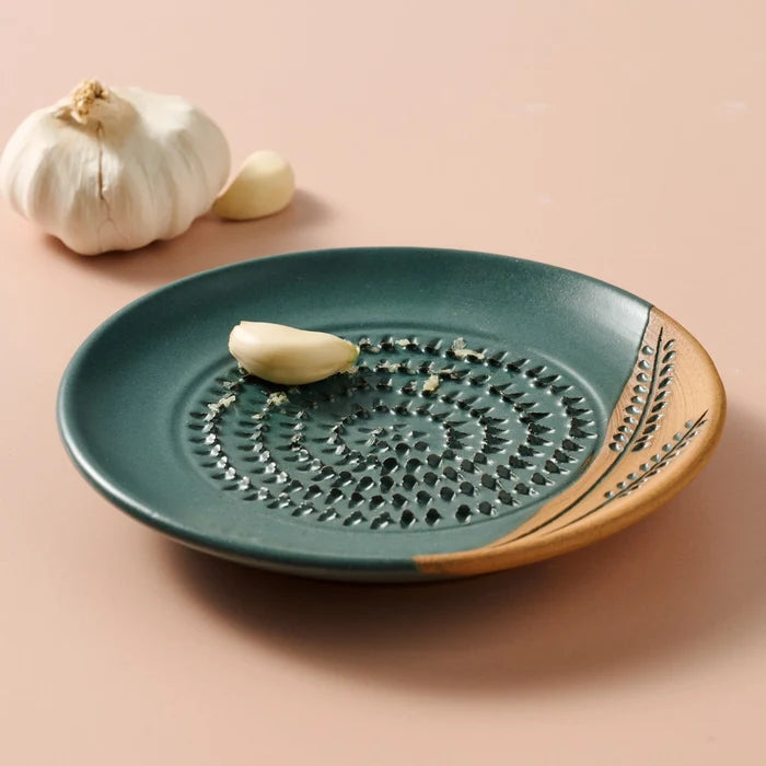 Ceramic grater dish with decorative edge on a beige background