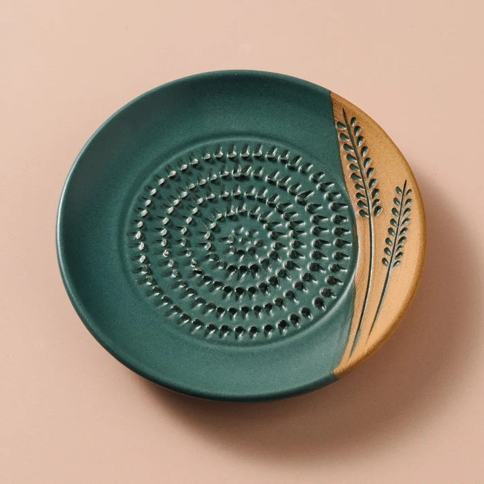 Ceramic grater plate with green and beige design on a beige background