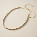Beaded necklace with gold and beige beads on a light background