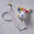 Crocheted llama measuring tape  on a concrete surface