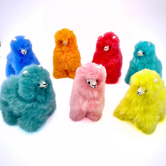 Seven small, colorful alpaca; stuffed toys on a white background.