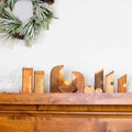 Wooden nativity on a mantelpiece with a Christmas wreath in the background
