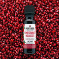 Burlap & Barrel Pomegranate Molasses bottle on a background of pomegranate seeds