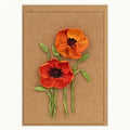 Two red orange cornhusk poppy flowers with green stems on a brown card