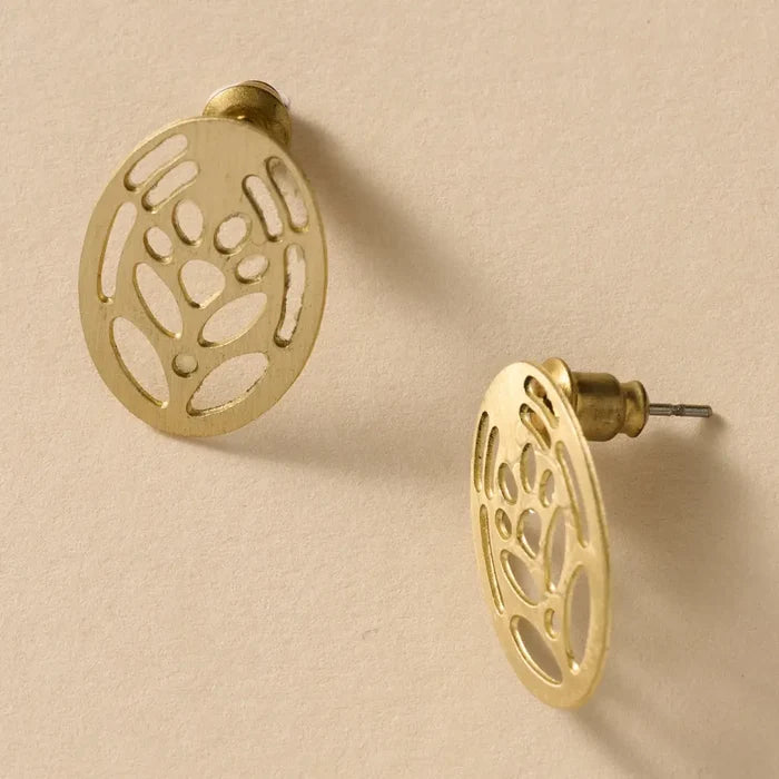 Gold earrings with intricate designs on a beige background