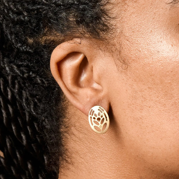 Close-up of an ear wearing a gold earring with intricate design