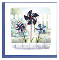 Three patriotic pinwheels decorations on a card with a scenic background.