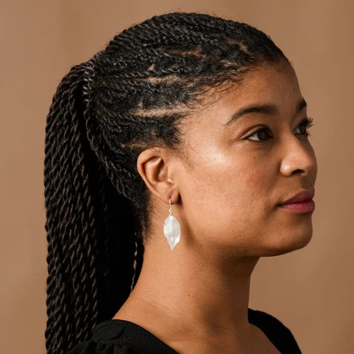 Woman with braided hair wearing a black top against a beige background