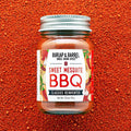 Jar of Burlap & Barrel Sweet Mesquite BBQ spice blend on a red background