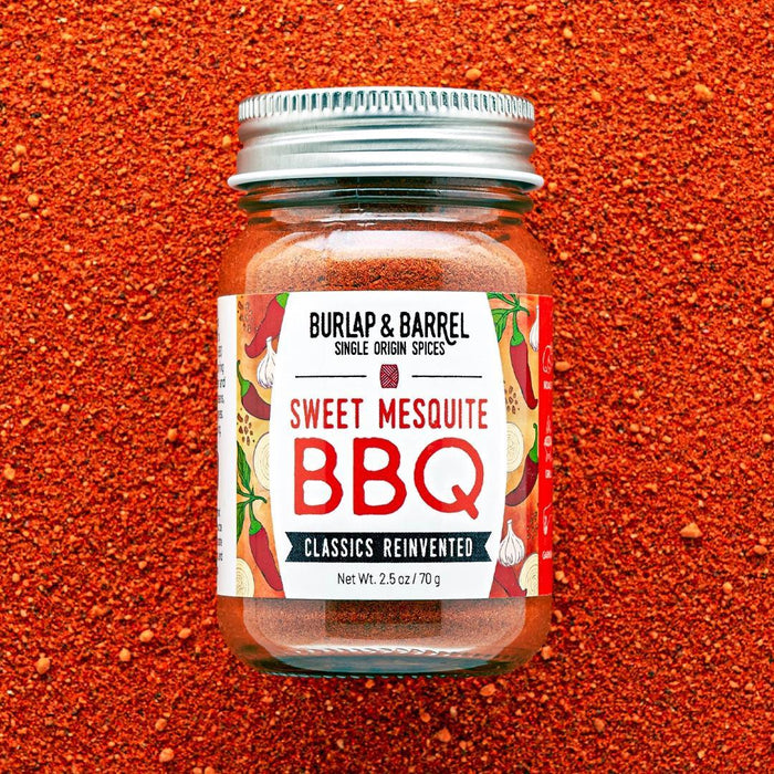 Jar of Burlap & Barrel Sweet Mesquite BBQ spice blend on a red background