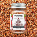 Jar of Burlap & Barrel Umami Steak Seasoning on a background of spices