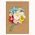 A rectangular kraft paper greeting card featuring a 3D paper flower bouquet with blue, white, red, pink, and yellow paper blossoms on a light beige background.